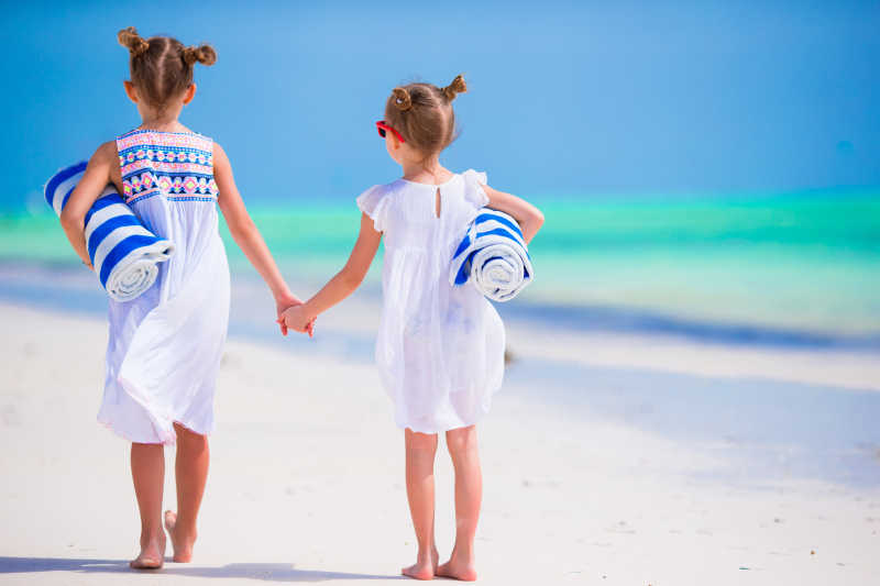 两个手拉手的小女孩在沙滩上散步