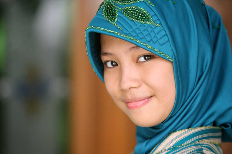 年轻的穆斯林女孩戴头巾躺在草地上