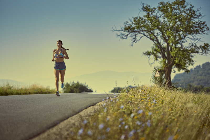 在城市的桥梁下慢跑的女跑步者图片_慢跑的女