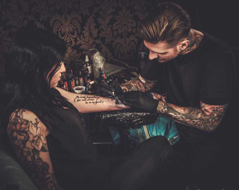 纹身师在年轻女孩的手上做纹身