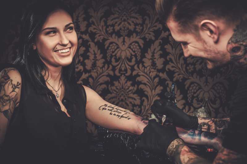 专业纹身师在年轻女孩的手上做纹身