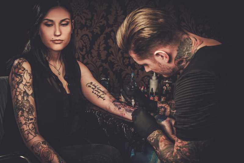 专业纹身师在年轻女孩的手上做纹身