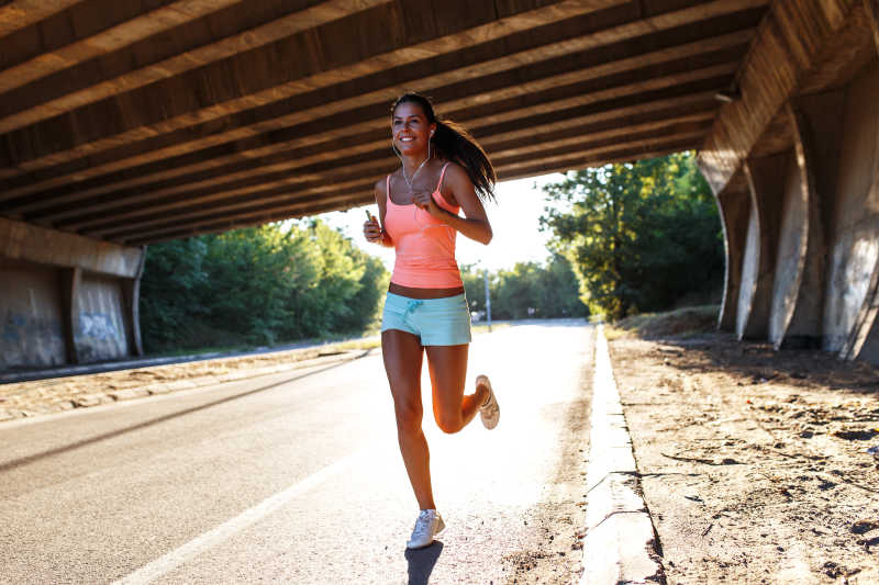 在城市的桥梁下慢跑的女跑步者图片_慢跑的女