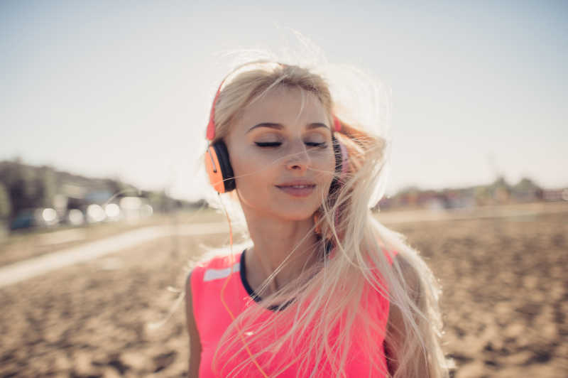 在沙滩上享受音乐的放松的金发美女