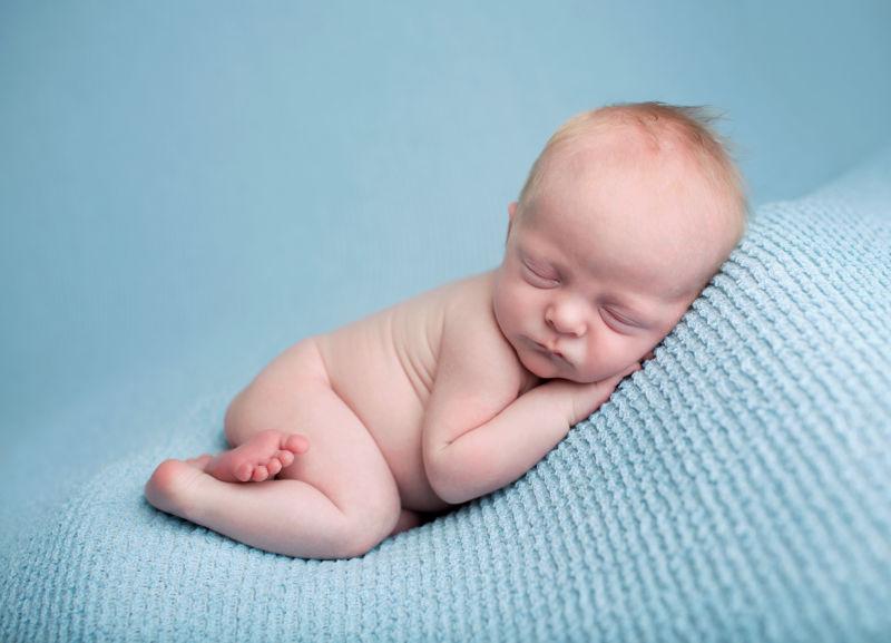 躺在毯子上的女婴抱着小脚丫