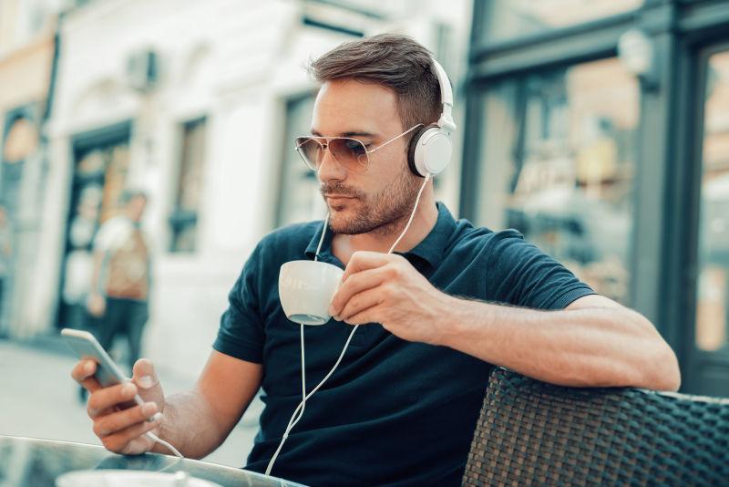 在咖啡馆听音乐玩手机喝咖啡的男人