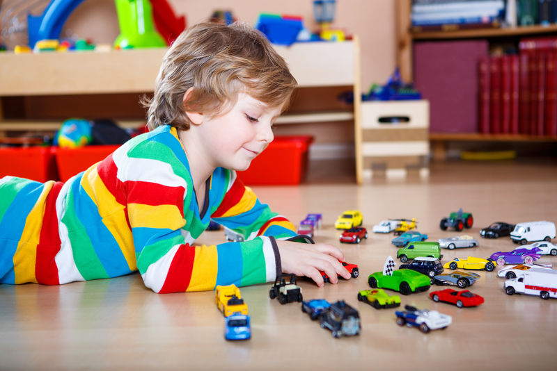 快乐有趣的小金发小孩在室内玩很多玩具车-男孩穿着彩色衬衫-在托儿所