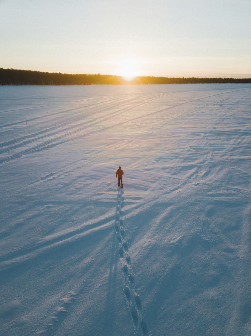 一个人在雪地上漫步欣赏日落
