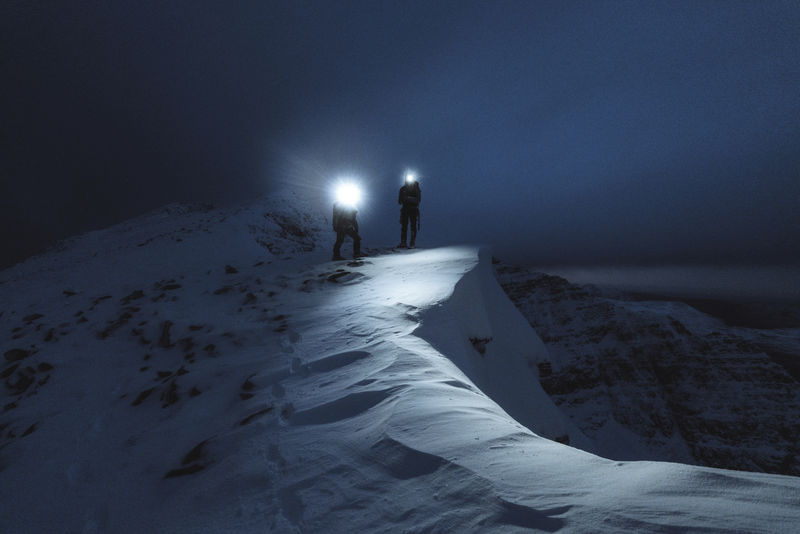 苏格兰利亚塔赫山脊登山者在寒冷的夜晚跋涉