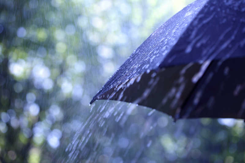 野外小孩子撑着雨水避雨