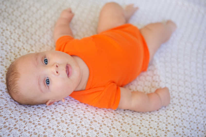 穿着橙色背心躺着的婴儿