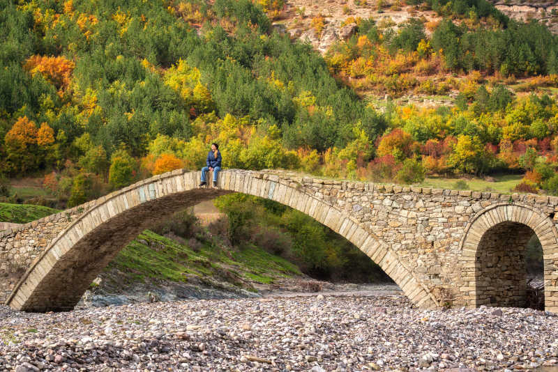 秋天的森林女人坐在石桥上