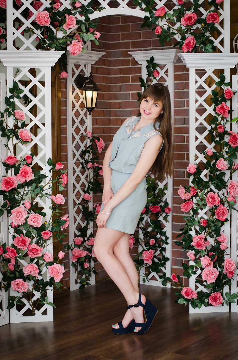 美丽的女孩在一个花拱门摆出姿势拍照