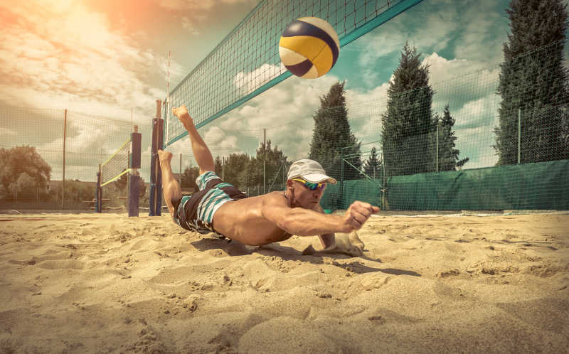 蓝天下在沙滩打排球的运动员