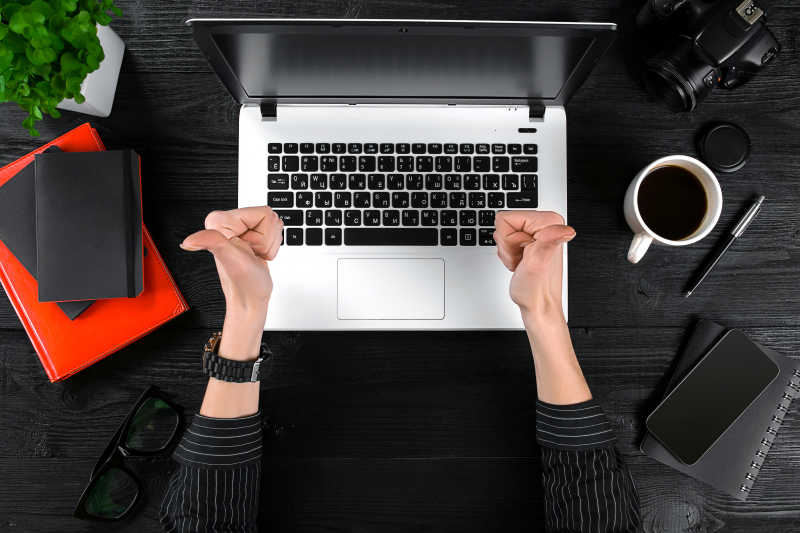 一位女士在办公室桌电脑前翘起大拇指
