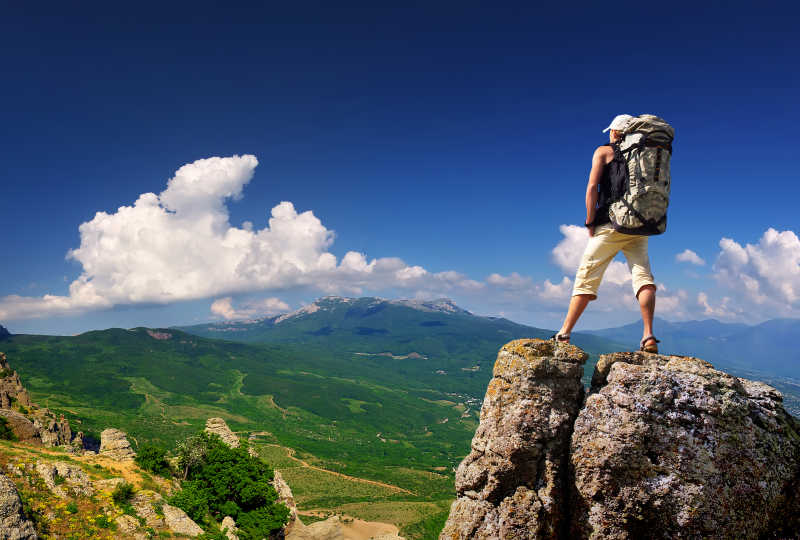 站在岩石上的登顶成功的人正在俯视山的风景