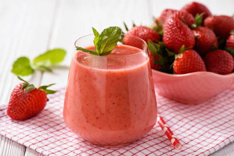 在木头桌子上的草莓奶昔和放在碗里的草莓
