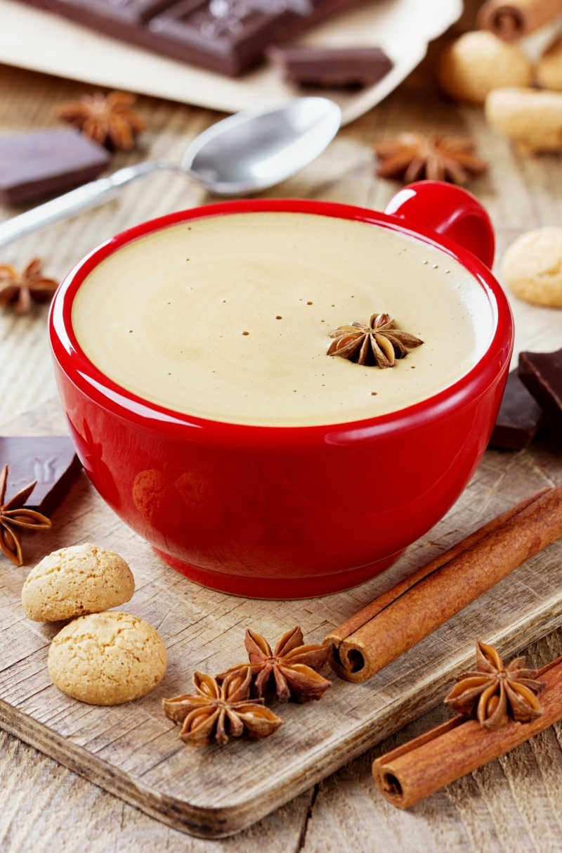 在一个红色的杯子里的咖啡饼干和香料在一个质朴的木制厨房板上