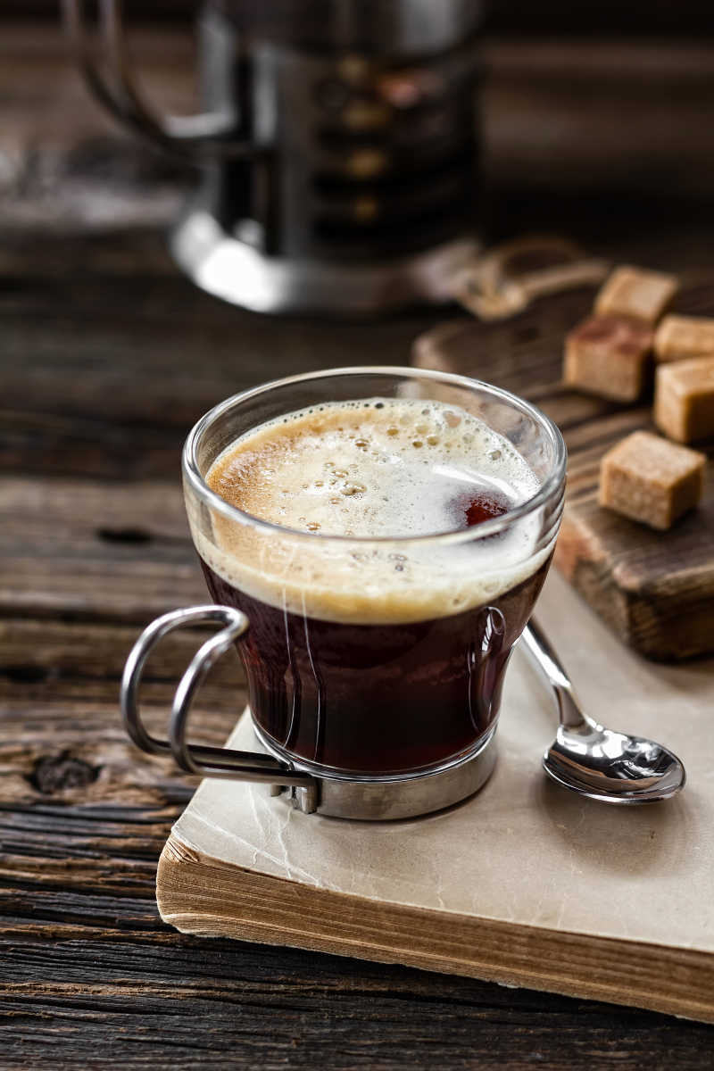 桌子上的玻璃咖啡杯旁边有调羹和红糖