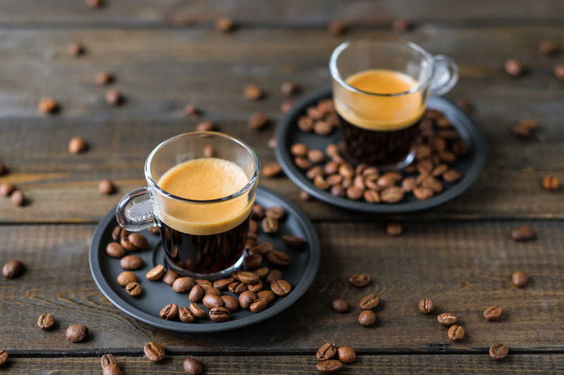 两杯意大利浓咖啡和咖啡豆放在木桌上