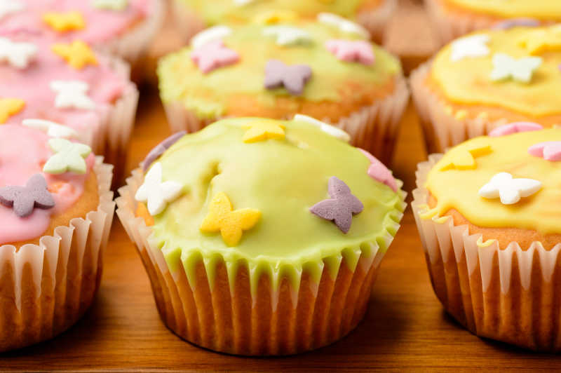 松饼覆盖着五颜六色的冰舒加在木板上