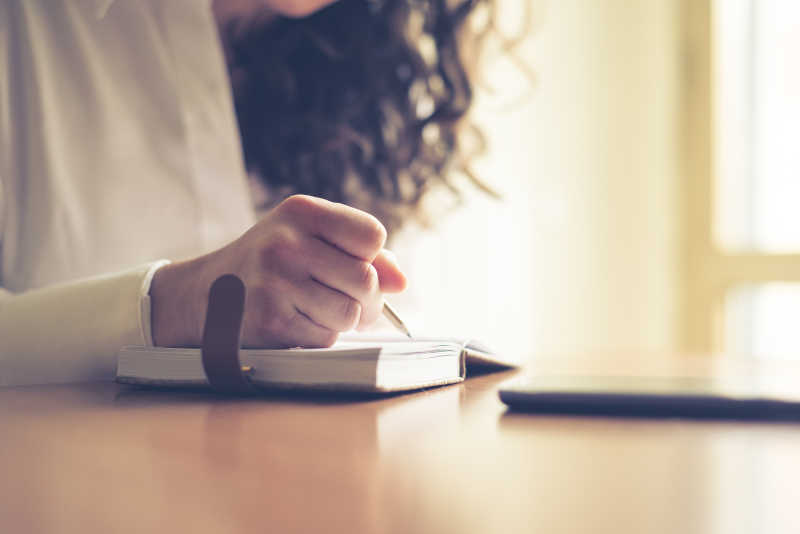 女性在家写作和日记旁边放着手机