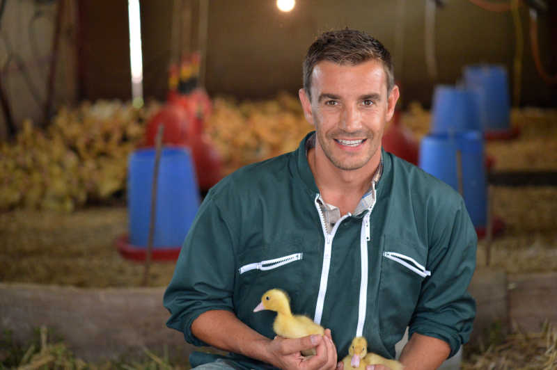 快乐的农民和他怀里抱着的刚出生小鸭