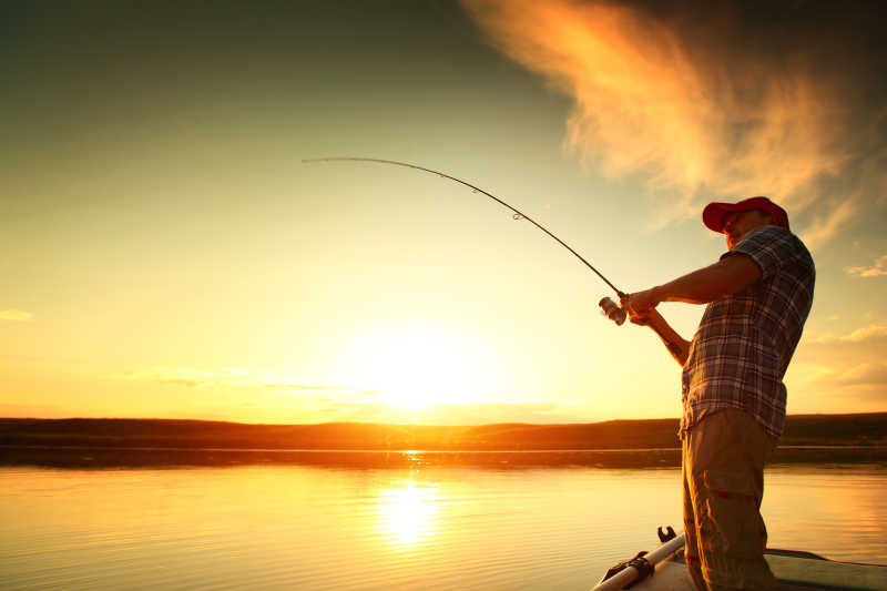 一个男人在落日的湖边钓鱼