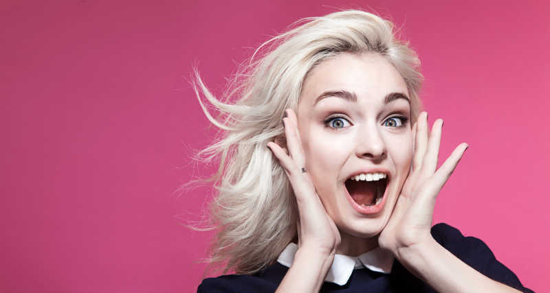 快乐的女孩在粉红色的背景下呐喊