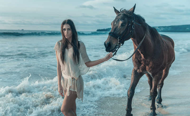 牵着马走在海边的美女