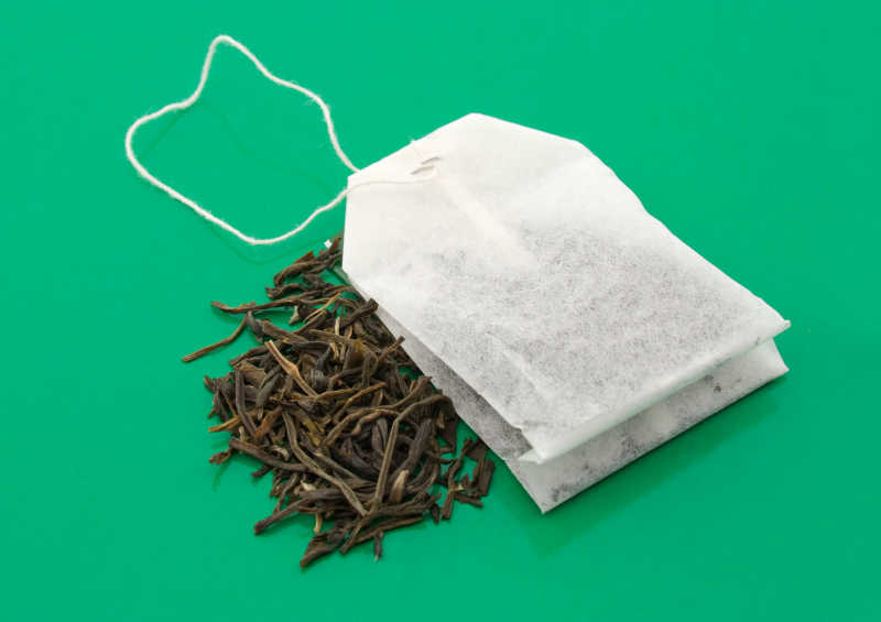 绿色背景上晒干的茶叶和茶包
