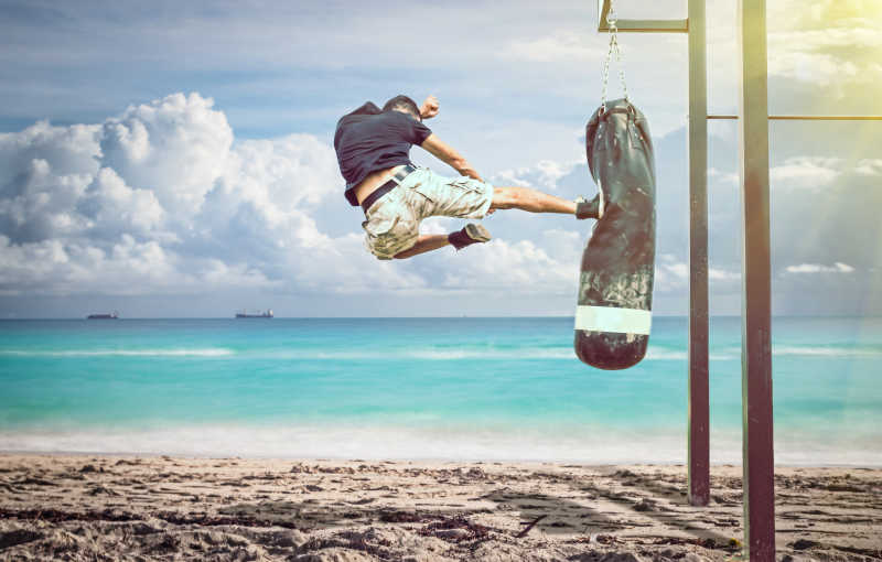 在沙滩上的脚踹沙袋的人