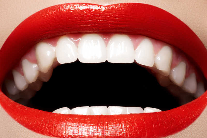 露出健康洁白的牙齿和涂着红色的口红的女人