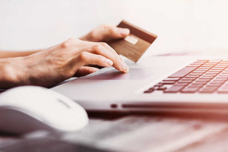 手持信用卡和使用笔记本电脑