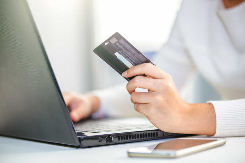手持信用卡使用笔记本电脑网购
