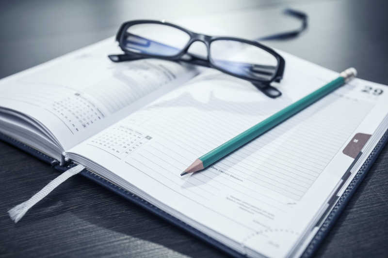 笔记本上放着眼镜盒铅笔