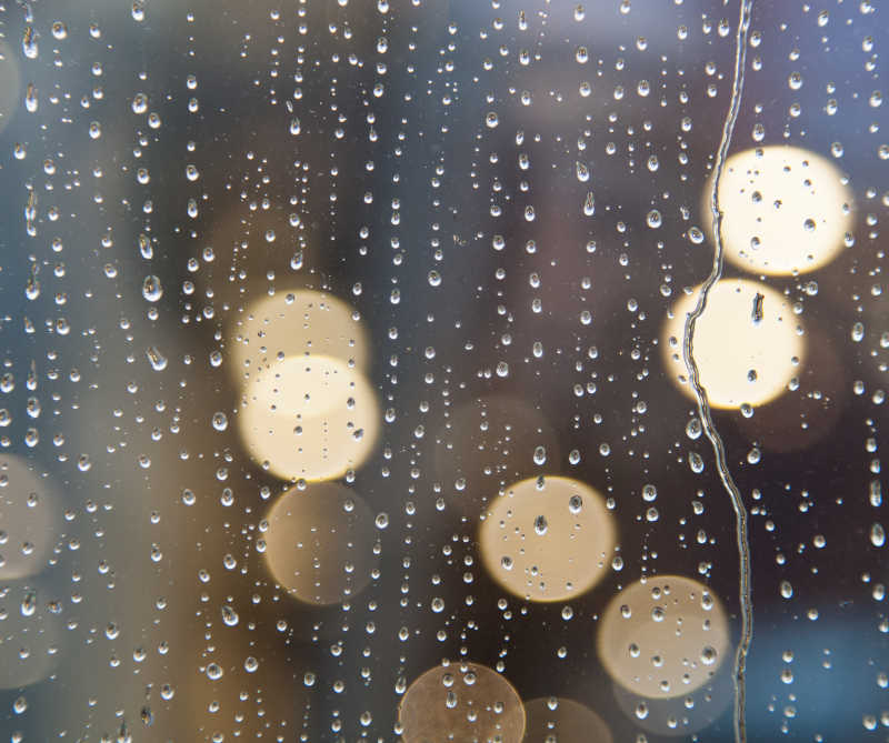 用抽象光在窗上滴下雨水水滴