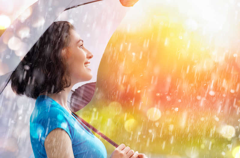 微笑的女人打着伞面对幸福的雨