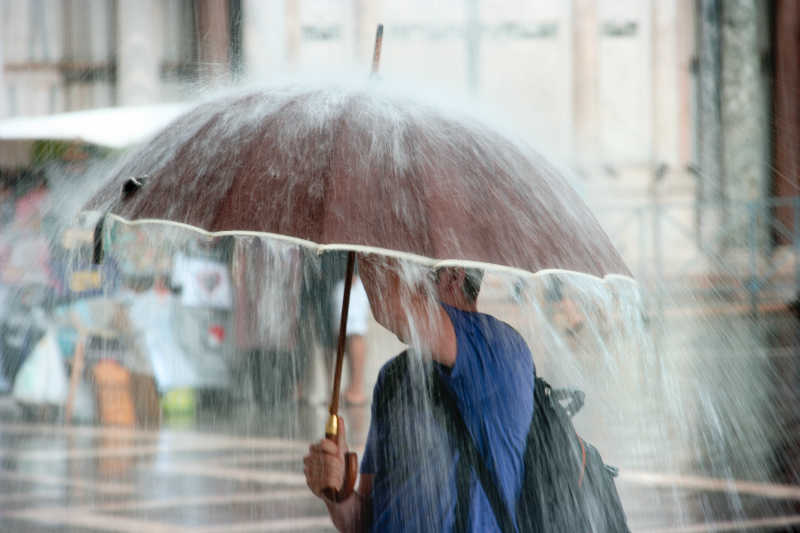 举着伞下着大雨的男性