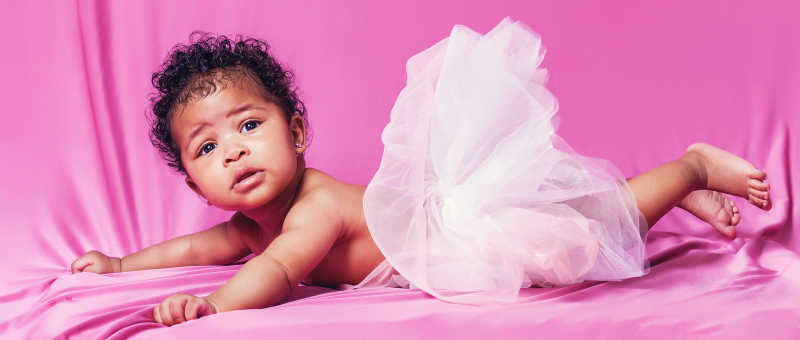 可爱的婴儿穿着粉色的纱裙趴在玫红色的布上