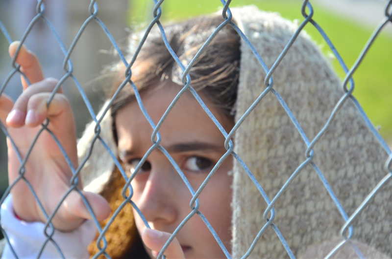 一个小女孩趴在网框上透露着悲哀的眼神