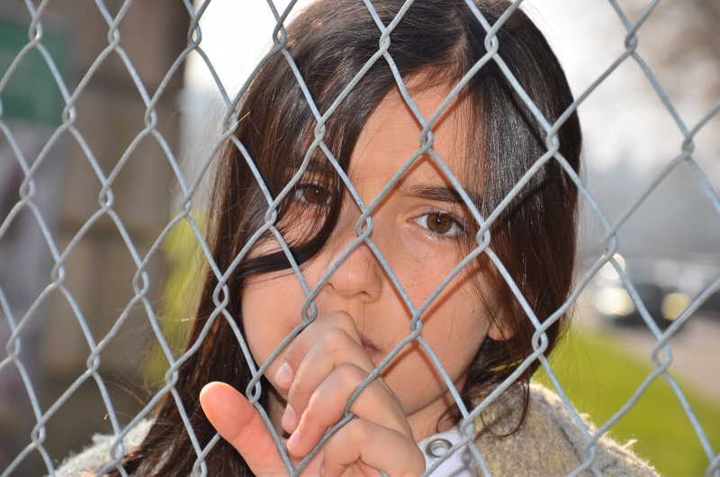 一个小女孩手抓着网框上透露着悲哀的眼神