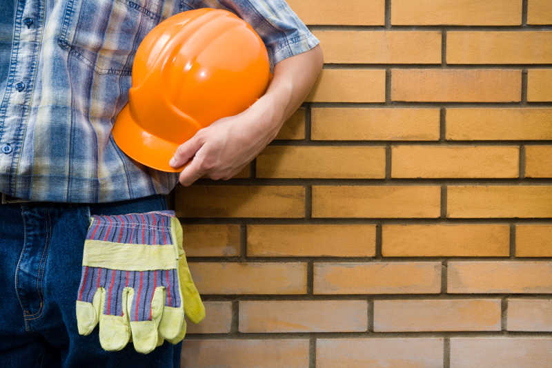 建筑工人手拿安全帽和墙