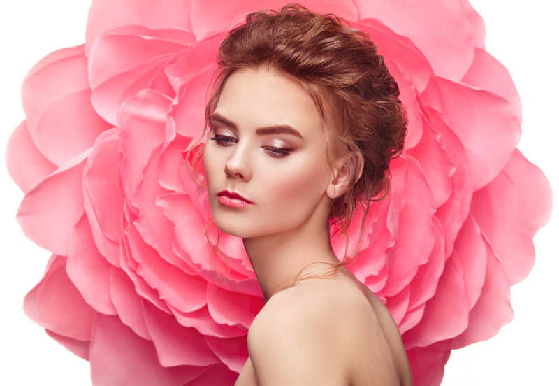 美丽的女人在一朵大花背景下