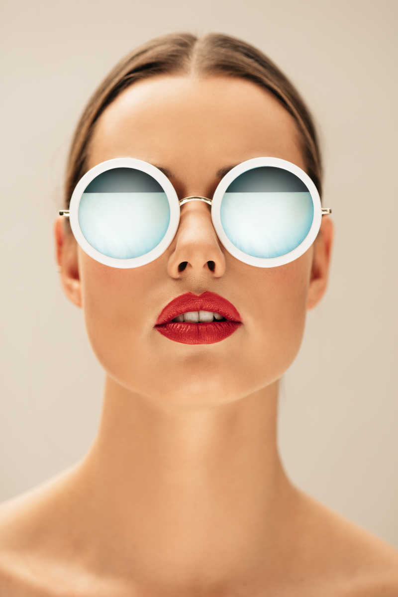 时尚美丽的女模特眨眼戴着眼镜