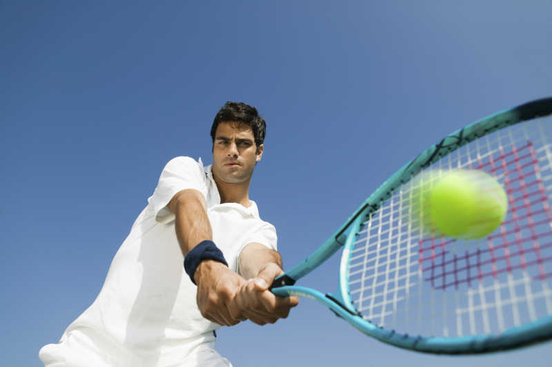 蓝天下用网球拍接住网球的网球运动员