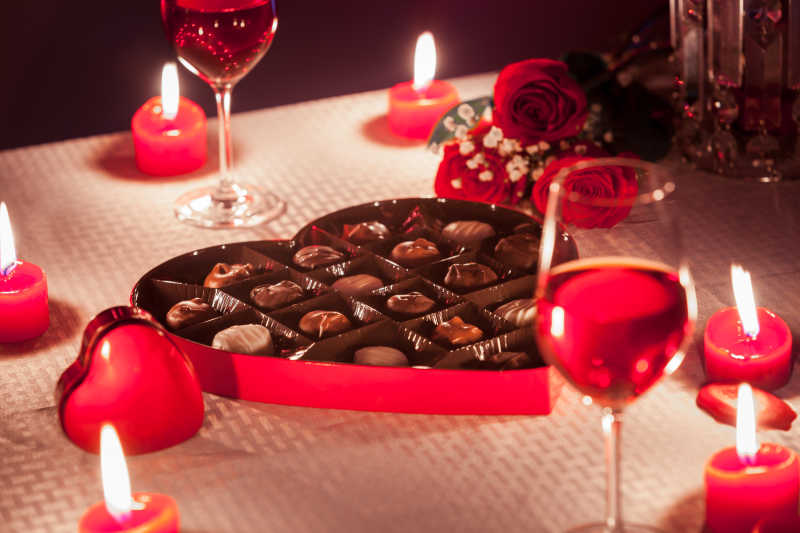 情人节浪漫晚餐包括巧克力葡萄酒蜡烛和桌上的红玫瑰