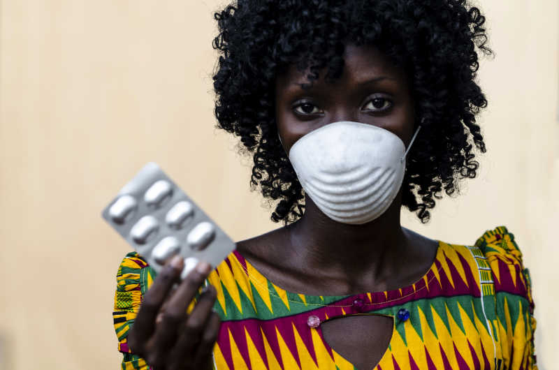 戴着口罩的黑人医生给一些胶囊