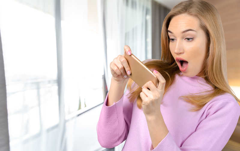 女人惊讶的使用着手机