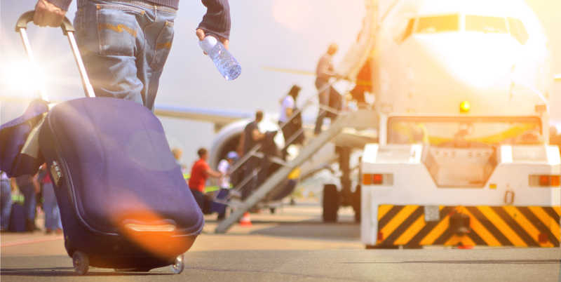 乘客拉着行李箱在机场准备登机